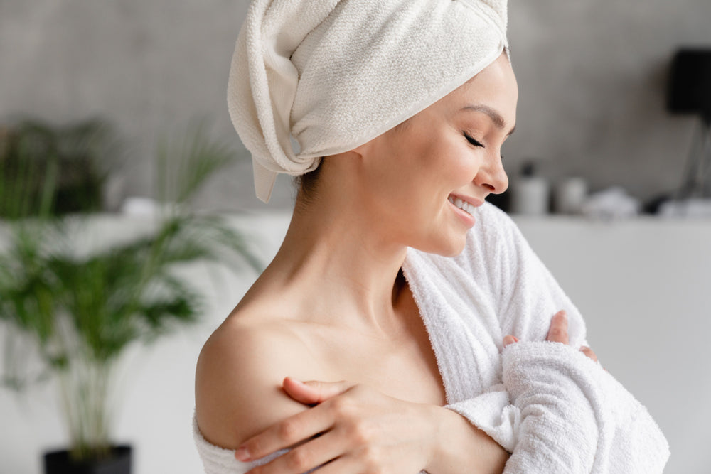 Woman in her bathrobe looking relaxed after her bath using Elixir Mind Body Botanicals bath products