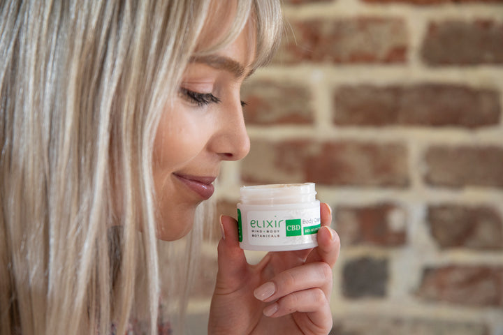 Woman smelling Elixir Mind Body Botanicals CBD Body Cream