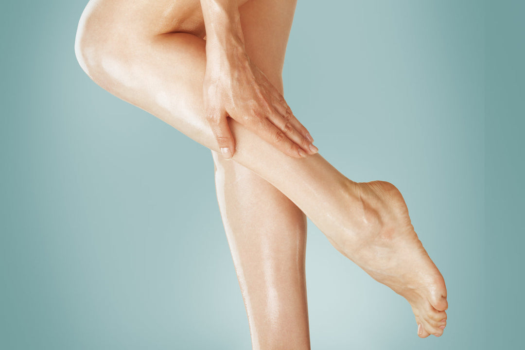 Woman applying Elixir Mind Body Botanicals Massage & Body Oil to her legs
