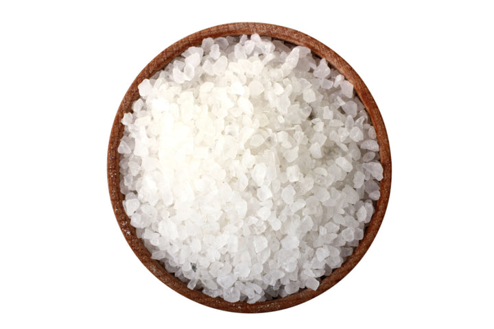 A bowl of Elixir Mind Body Botanicals Mineral Soaking Salt crystals on a white background