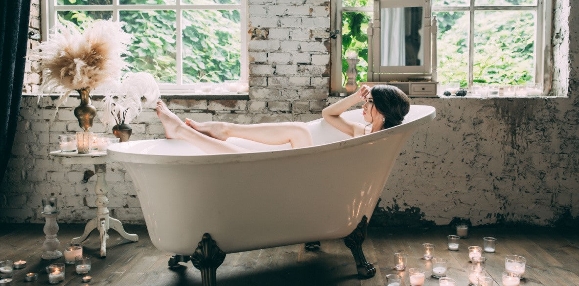 woman taking a relaxing bath  in a clawfoot tub using Elixir Mind Body Botanicals bath products