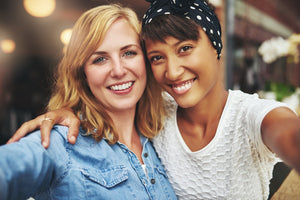 Photo of two women with their arms around each other smiling.