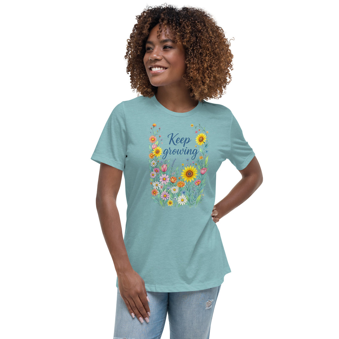 Front view of a smiling woman wearing her relaxed heather blue short-sleeved t-shirt with a colorful, floral design on the front that says "Keep Growing."