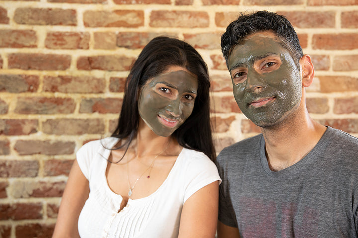 Smiling man and woman with Elixir Mind Body Botanicals Mineral Mud Mask on their faces waiting for it to dry