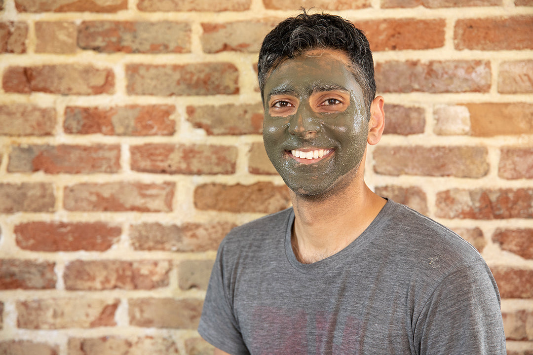 Smiling man using Elixir Mind Body Botanicals Mineral Mud Mask on his face